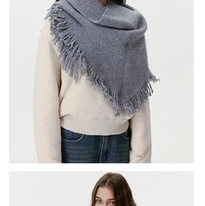 Close-up detail of grey wool-blend triangle scarf with decorative fringe tassels