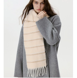 Detail of wool blend striped scarf with fringe tassels worn over a grey tweed coat