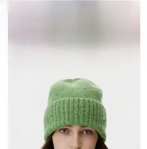 Detail of grass green knit beanie showing soft wool texture and ribbed cuff design