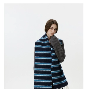 Detail of blue and white striped wool scarf with soft fringes on a grey sweater