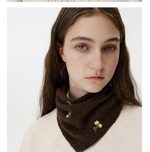 Detail of dark brown knitted neck warmer featuring delicate yellow floral embroidery accents