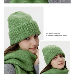 Detail of green knitted beanie and matching thick scarf with soft mohair texture