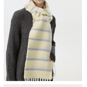 Detailed view of yellow and gray striped wool blend scarf with soft fringe and knit texture
