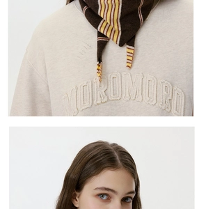 Detail of the striped knitted neck scarf paired with a cream-white letter sweatshirt