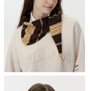 Detail of striped knit triangular scarf in dark brown with retro patterns on model