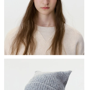 Detailed close-up of wool blend cat ear beanie and cream knit sweater texture
