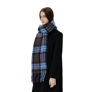 Blue and brown plaid winter scarf with fringe detail on a female model with white background