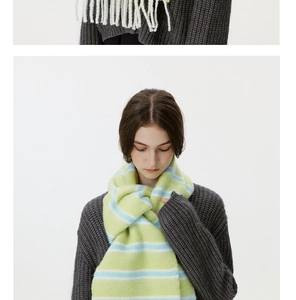 Close-up of soft green and blue striped wool blend scarf featuring delicate white tassels