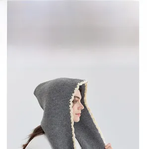 Detail of grey knitted hooded scarf with cream scalloped edges for winter warmth