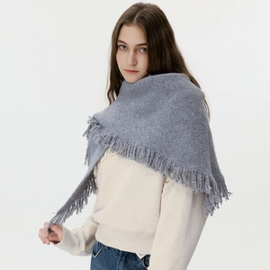 Gray chunky knit triangle scarf with long tassels draped over a model on white background