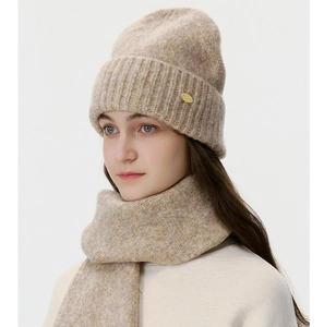 Macro detail of beige thick knitted beanie and matching scarf set with metal logo tag