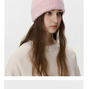 Close-up of pink wool blend knit beanie and beige sweatshirt with triangular stitching