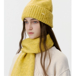 Detail of yellow knit beanie and scarf set featuring textured ribbing and metal logo