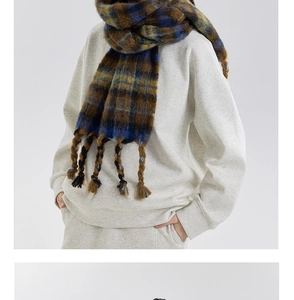 Close-up of thick plaid scarf featuring navy and caramel checks with braided tassels