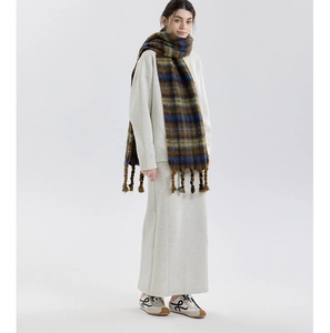 Detailed view of the mixed-color plaid scarf with woven tassels on a minimalist outfit