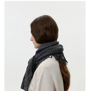 Detailed view of dark grey knitted scarf with thick fringe and cozy wool texture