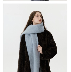 Detail of light blue fuzzy wool blend scarf with fringe worn with a brown fleece coat