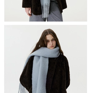 Detail of wool blend tassel scarf in light blue paired with a brown plush jacket
