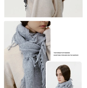 Detail of light grey wool blend knitted scarf with soft tassel edges and cozy texture