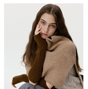 Detailed close-up of dark brown knitted arm warmers paired with a beige knit shrug