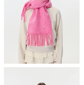 Detail of bright pink knitted scarf featuring long tassel fringe and thick fuzzy texture
