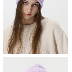 Detail of lavender knit beanie with large faux fur pompom showing soft texture and ribbed design