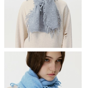 Detail of light blue wool blend scarf showing soft fringe and warm knit texture