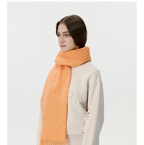 Detailed macro of bright orange knitted scarf featuring long tassels and soft mohair texture