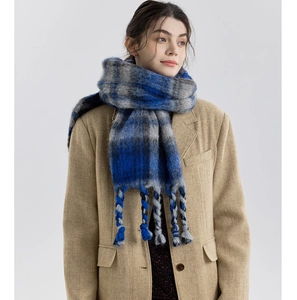 Close-up of thick blue and grey plaid scarf featuring chunky hand-woven tassel details