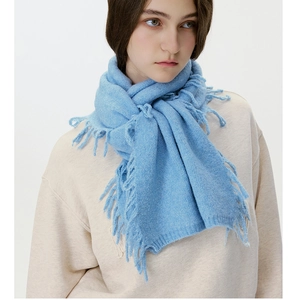 Detail of light blue wool blend scarf with fringe tassels worn by a model in studio