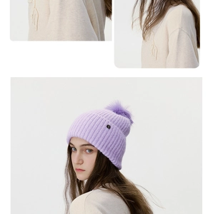 Detail of purple knitted beanie with large soft pom-pom and metallic logo accent
