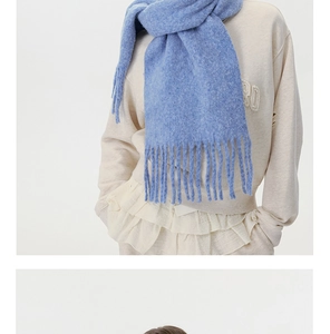Detailed close-up of light blue knitted scarf with soft wool texture and fringe edges