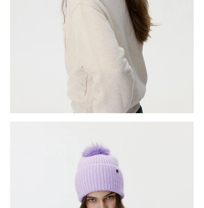 Close-up of a lavender knitted beanie with a large faux fur pom-pom and soft texture