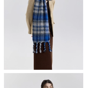 Close-up of thick blue and grey plaid scarf showing soft wool texture and braided fringe details