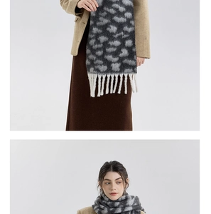 Detail of thick leopard print scarf featuring chunky white fringe tassels and soft knit texture