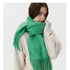 Detail shot of bright green thick knitted scarf with long tassels and soft plush texture