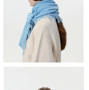 Close-up of light blue knit scarf texture with fringe details and soft wool blend material