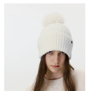 Close-up of white ribbed knit beanie with soft pom-pom and metal tag detail
