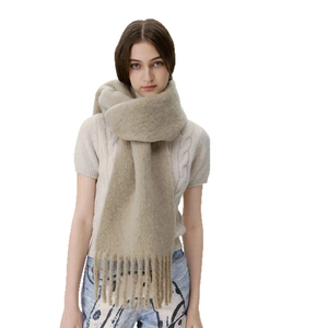 Beige wool blend scarf with tassels and fuzzy texture worn by model in a studio setting