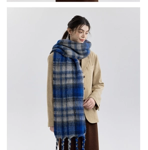 Detailed close-up of blue-grey plaid scarf texture with handcrafted long tassels