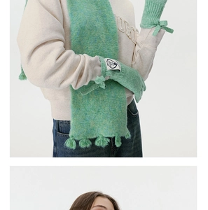 Detail von mintgrünen Strickhandschuhen mit Schleife und passendem Fransenschal