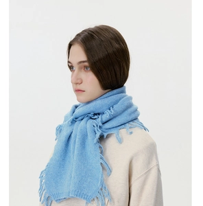 Detailed view of sky blue knitted wool scarf with long tassel edges on female model
