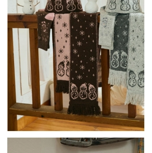 Close-up of wool blend knit scarf featuring cute snowman patterns and fringe details