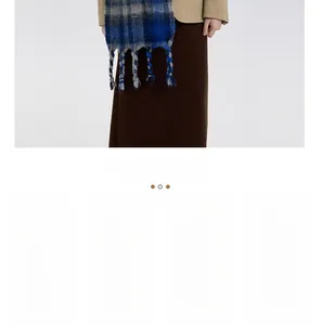 Blue and gray plaid scarf with fringe detail worn over a stylish light brown blazer