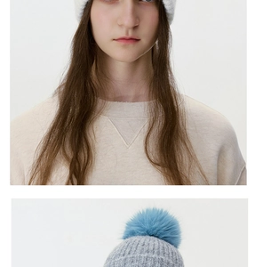 Close-up of thick knit winter hat featuring a soft bicolor pom-pom detail and white texture