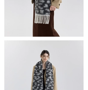 Detailed view of leopard print scarf with white tassels on soft brushed fabric texture