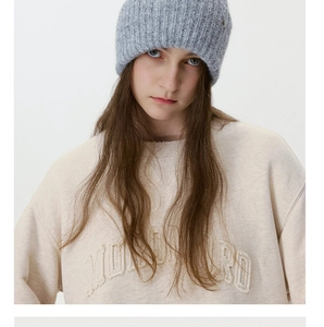 Close-up of grey chunky knit hat texture and embroidered beige cotton sweatshirt detail