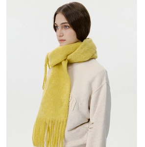 Detail of bright yellow knitted scarf showing long fringe tassels and thick warm texture