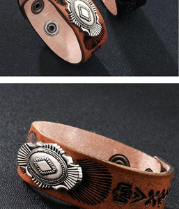 Dettaglio di bracciale in pelle marrone vintage con totem argento e rune incise