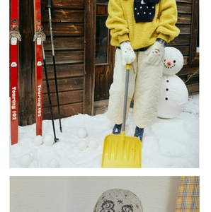 Detail of gray knitted winter hat with cute cartoon snowman jacquard pattern in snow